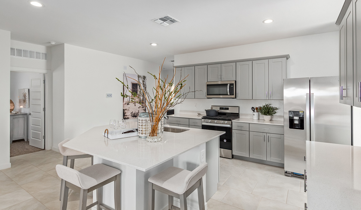 Step into The Kingston at Barnett Village, Marana, Arizona – a perfect blend of comfort, modern living, and energy efficiency. This thoughtfully crafted one-story home spans 2,068 square feet and offers four bedrooms and two bathrooms, ideal for families of all sizes.  The open-concept design features a spacious great room that effortlessly connects with the kitchen and dining area, creating an inviting central hub for everyday living and entertaining. The kitchen is equipped with contemporary appliances and a pantry, offering ample storage and convenience for meal preparation.  The primary bedroom, located at the rear of the home, provides a peaceful retreat with a private ensuite bathroom and a generous walk-in closet. The additional three bedrooms are positioned at the front of the house, offering versatility for use as guest rooms, a home office, or children’s bedrooms. Step outside to the covered patio, a perfect spot to enjoy the beautiful Arizona weather, whether for morning coffee or evening relaxation.  The Kingston also boasts a covered patio, perfect for enjoying Arizona’s beautiful desert evenings. Whether it’s morning coffee or evening relaxation, this outdoor space extends your living area into the serene landscape of Barnett Village.  Built with energy efficiency as a priority, the Kingston includes smart home technology, which not only simplifies daily living but also helps reduce utility costs. A two-car garage provides ample parking and additional storage space, enhancing the home’s functionality.