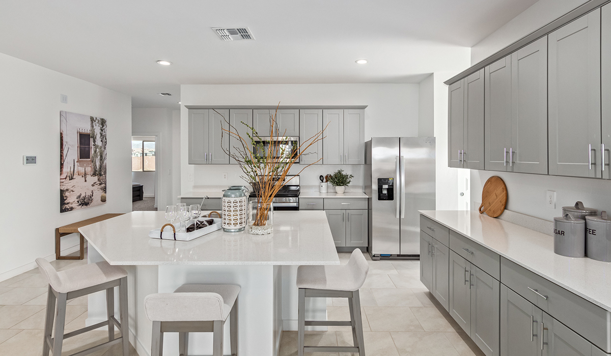 Step into The Kingston at Barnett Village, Marana, Arizona – a perfect blend of comfort, modern living, and energy efficiency. This thoughtfully crafted one-story home spans 2,068 square feet and offers four bedrooms and two bathrooms, ideal for families of all sizes.  The open-concept design features a spacious great room that effortlessly connects with the kitchen and dining area, creating an inviting central hub for everyday living and entertaining. The kitchen is equipped with contemporary appliances and a pantry, offering ample storage and convenience for meal preparation.  The primary bedroom, located at the rear of the home, provides a peaceful retreat with a private ensuite bathroom and a generous walk-in closet. The additional three bedrooms are positioned at the front of the house, offering versatility for use as guest rooms, a home office, or children’s bedrooms. Step outside to the covered patio, a perfect spot to enjoy the beautiful Arizona weather, whether for morning coffee or evening relaxation.  The Kingston also boasts a covered patio, perfect for enjoying Arizona’s beautiful desert evenings. Whether it’s morning coffee or evening relaxation, this outdoor space extends your living area into the serene landscape of Barnett Village.  Built with energy efficiency as a priority, the Kingston includes smart home technology, which not only simplifies daily living but also helps reduce utility costs. A two-car garage provides ample parking and additional storage space, enhancing the home’s functionality.