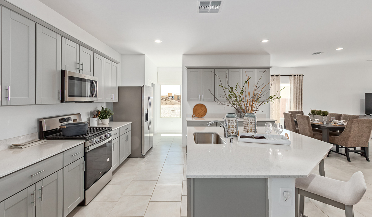 Step into The Kingston at Barnett Village, Marana, Arizona – a perfect blend of comfort, modern living, and energy efficiency. This thoughtfully crafted one-story home spans 2,068 square feet and offers four bedrooms and two bathrooms, ideal for families of all sizes.  The open-concept design features a spacious great room that effortlessly connects with the kitchen and dining area, creating an inviting central hub for everyday living and entertaining. The kitchen is equipped with contemporary appliances and a pantry, offering ample storage and convenience for meal preparation.  The primary bedroom, located at the rear of the home, provides a peaceful retreat with a private ensuite bathroom and a generous walk-in closet. The additional three bedrooms are positioned at the front of the house, offering versatility for use as guest rooms, a home office, or children’s bedrooms. Step outside to the covered patio, a perfect spot to enjoy the beautiful Arizona weather, whether for morning coffee or evening relaxation.  The Kingston also boasts a covered patio, perfect for enjoying Arizona’s beautiful desert evenings. Whether it’s morning coffee or evening relaxation, this outdoor space extends your living area into the serene landscape of Barnett Village.  Built with energy efficiency as a priority, the Kingston includes smart home technology, which not only simplifies daily living but also helps reduce utility costs. A two-car garage provides ample parking and additional storage space, enhancing the home’s functionality.