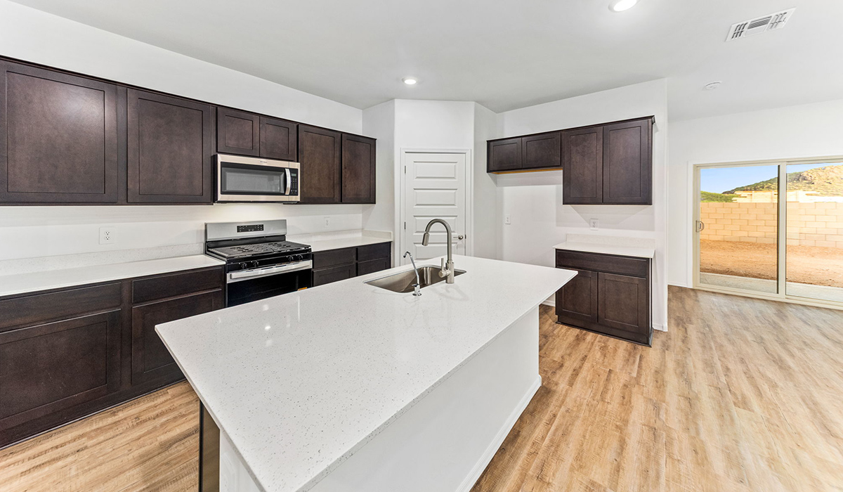 Step into The Dalea at Barnett Village, Marana, Arizona – a perfect blend of comfort, modern living, and energy efficiency. This thoughtfully crafted one-story home spans 2,224 square feet and offers five bedrooms and 3 bathrooms, ideal for families of all sizes.  The open-concept design features a spacious great room that effortlessly connects with the kitchen and dining area, creating an inviting central hub for everyday living and entertaining. The kitchen is equipped with contemporary appliances and a pantry, offering ample storage and convenience for meal preparation.  The primary bedroom, located at the rear of the home, provides a peaceful retreat with a private ensuite bathroom and a generous walk-in closet. The additional four bedrooms are positioned at the front of the house, offering versatility for use as guest rooms, a home office, or children’s bedrooms.  The Dalea floor plan offers the option of a three-car tandem garage, perfect for additional space and larger sized vehicles. Whether it’s morning coffee or evening relaxation, this outdoor space extends your living area into the serene landscape of Barnett Village.  Built with energy efficiency as a priority, the Dalea includes smart home technology, which not only simplifies daily living but also helps reduce utility costs.