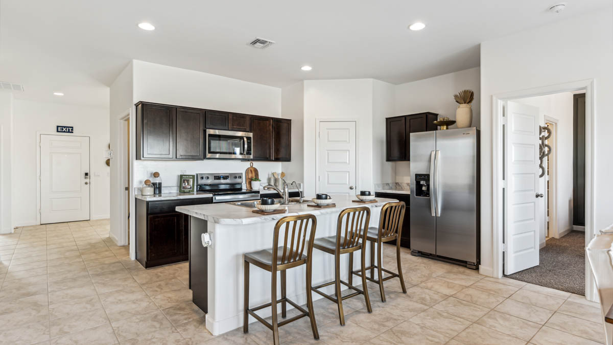 Explore The Dalton at Barnett Village in Marana, Arizona – a spacious 1,569 sq. ft. single-story new home designed to accommodate both comfort and convenience for modern living.  As you step through the front porch and into the welcoming entryway, you're immediately led into a thoughtfully designed space that maximizes every square foot. To the left, you’ll find Bedroom 4, ideal for guests or a home office, offering privacy and easy access to the main living areas.  Continuing through the home, you’ll enter the heart of The Dalton – an expansive great room that seamlessly connects to the dining area and kitchen. This open-concept space is perfect for entertaining or everyday family living, allowing for a fluid transition from cooking to dining to relaxation. The kitchen is equipped with sleek granite countertops, modern appliances, a walk-in pantry, and an island that doubles as a breakfast bar, providing ample space for meal prep and casual dining.  Adjacent to the great room, a hallway leads to three additional bedrooms, including the spacious master suite. The master bedroom offers a serene retreat with a large walk-in closet and an en-suite bathroom featuring dual vanities and a walk-in shower. The two secondary bedrooms share a well-appointed full bathroom, making it convenient for family members or guests.  The Dalton also includes a utility room that adds functionality and storage options to the home, as well as direct access to a two-car garage.  Step outside from the great room to the covered patio – a perfect spot to enjoy Arizona’s beautiful weather year-round, whether you’re sipping your morning coffee or hosting an evening barbecue.  Designed with energy efficiency in mind, The Dalton at Barnett Village is DOE Zero Energy Ready Home certified, ensuring long-term savings and a comfortable living environment.  *Images shown are for reference only. They depict the Dalton model home and may not represent the actual home.