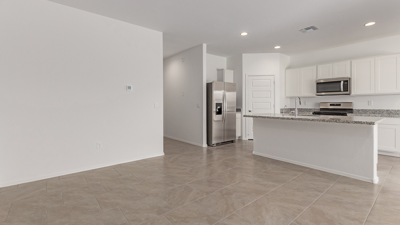 Discover The Easton at Barnett Village in Marana, Arizona – a spacious 1,701 sq. ft. single-story new home designed to offer both style and functionality for today’s modern family.  As you enter through the charming front porch, you’re welcomed into a thoughtful layout that makes every square foot count. Situated near the entrance you'll find the first bedroom, offering flexibility as a guest room, home office, or a cozy retreat.  Continuing down the hall, you’re led into the expansive great room, which flows seamlessly into the dining area and kitchen. This open-concept design ensures that the heart of the home is always connected, whether you’re preparing meals, dining, or relaxing with loved ones. The kitchen features sleek quartz countertops, a spacious center island, modern appliances, and a walk-in pantry that offers ample storage for all your cooking essentials.  The great room opens up to a covered patio, an ideal space to unwind and enjoy Arizona’s beautiful desert sunsets. Whether you’re hosting a weekend barbecue or enjoying a quiet evening outdoors, this patio extends your living space into the scenic surroundings of Barnett Village.  Just off the great room, a private hallway leads to the primary bedroom, which is a true retreat within the home. The primary suite is generously sized and includes a large walk-in closet and an en-suite bathroom, offering both luxury and convenience.   The Easton also features two additional bedrooms, well-positioned to share a full bathroom. These rooms are ideal for family members, providing comfortable living spaces with plenty of natural light.  For added convenience, the home includes a utility room and direct access to a two-car garage, making daily routines smoother and more efficient.  Designed with energy efficiency in mind, The Easton at Barnett Village is DOE Zero Energy Ready Home certified, ensuring both sustainability and savings.